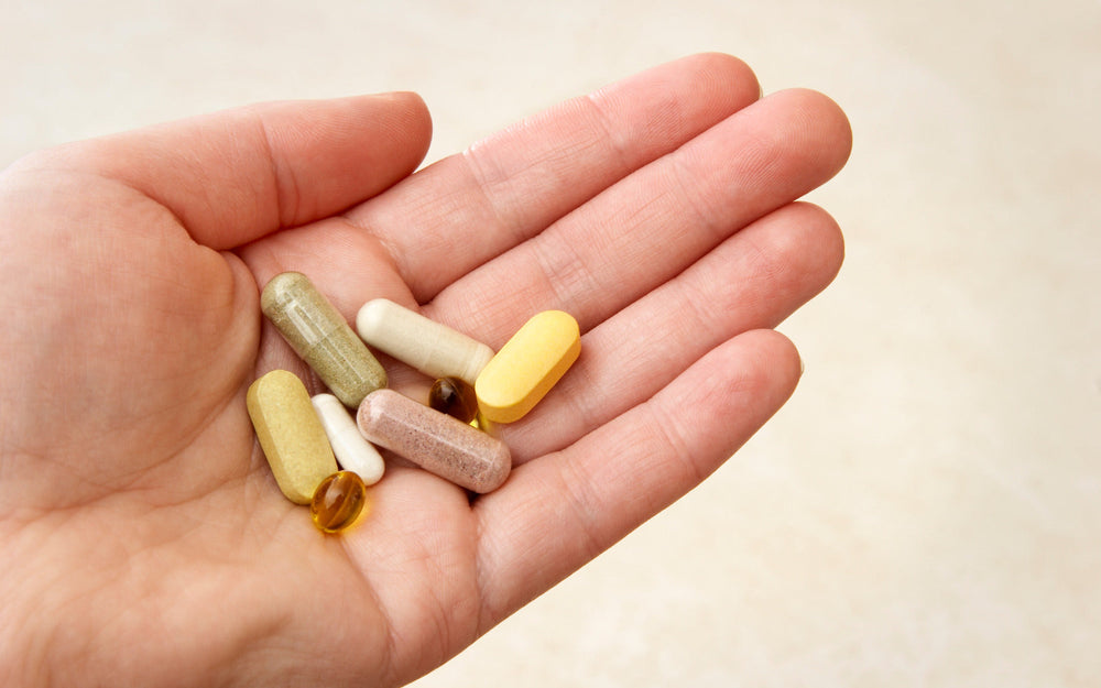 A hand holding various probiotic capsules, symbolizing the confusion around probiotic myths and the importance of choosing the right strain for gut health.